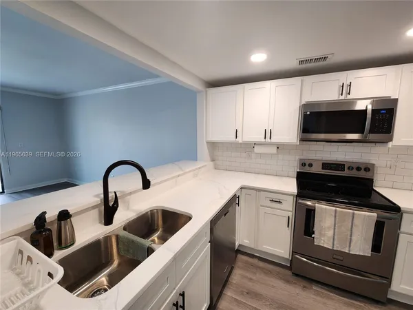 a kitchen with a microwave a stove and white cabinets