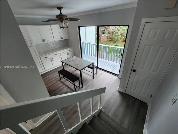 a view of a livingroom with furniture window wooden floor and a ceiling fan
