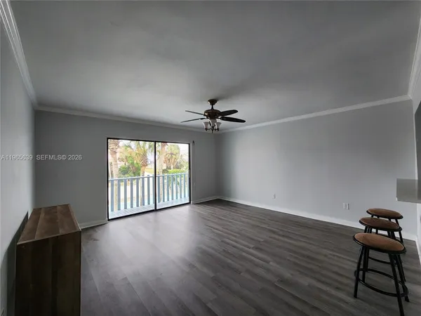 an empty room with wooden floor fan and windows
