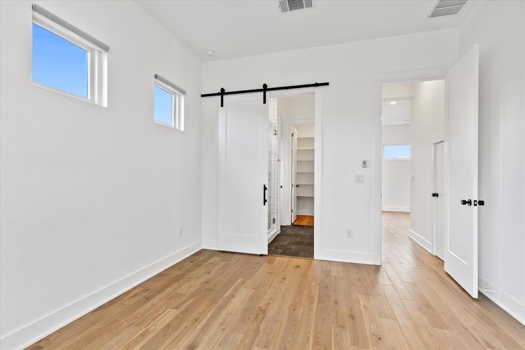 4020 Valley View Road, Unit A Austin, TX 78704 - Photo 8 of 17 Unfurnished bedroom featuring a barn door, light wood finished floors, and a spacious closet