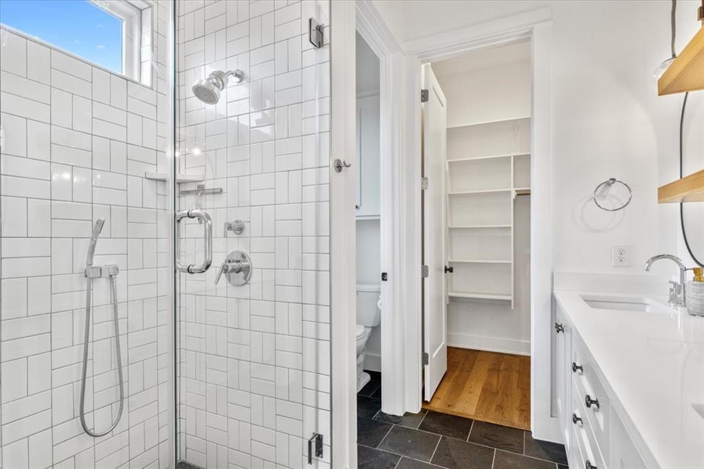 4020 Valley View Road, Unit A Austin, TX 78704 - Photo 9 of 17 Full bathroom with a walk in closet, double vanity, a shower stall, and dark tile patterned flooring