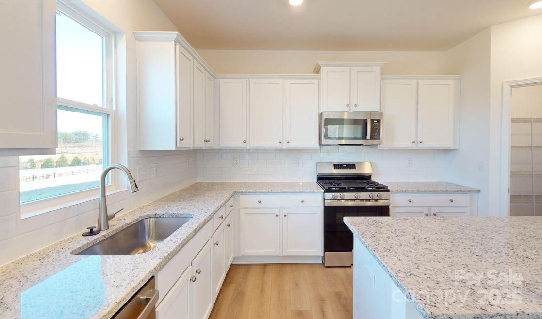 1805 Augustine Street Monroe, NC 28112 - Photo 8 of 17 a kitchen with stainless steel appliances granite countertop a sink stove and refrigerator