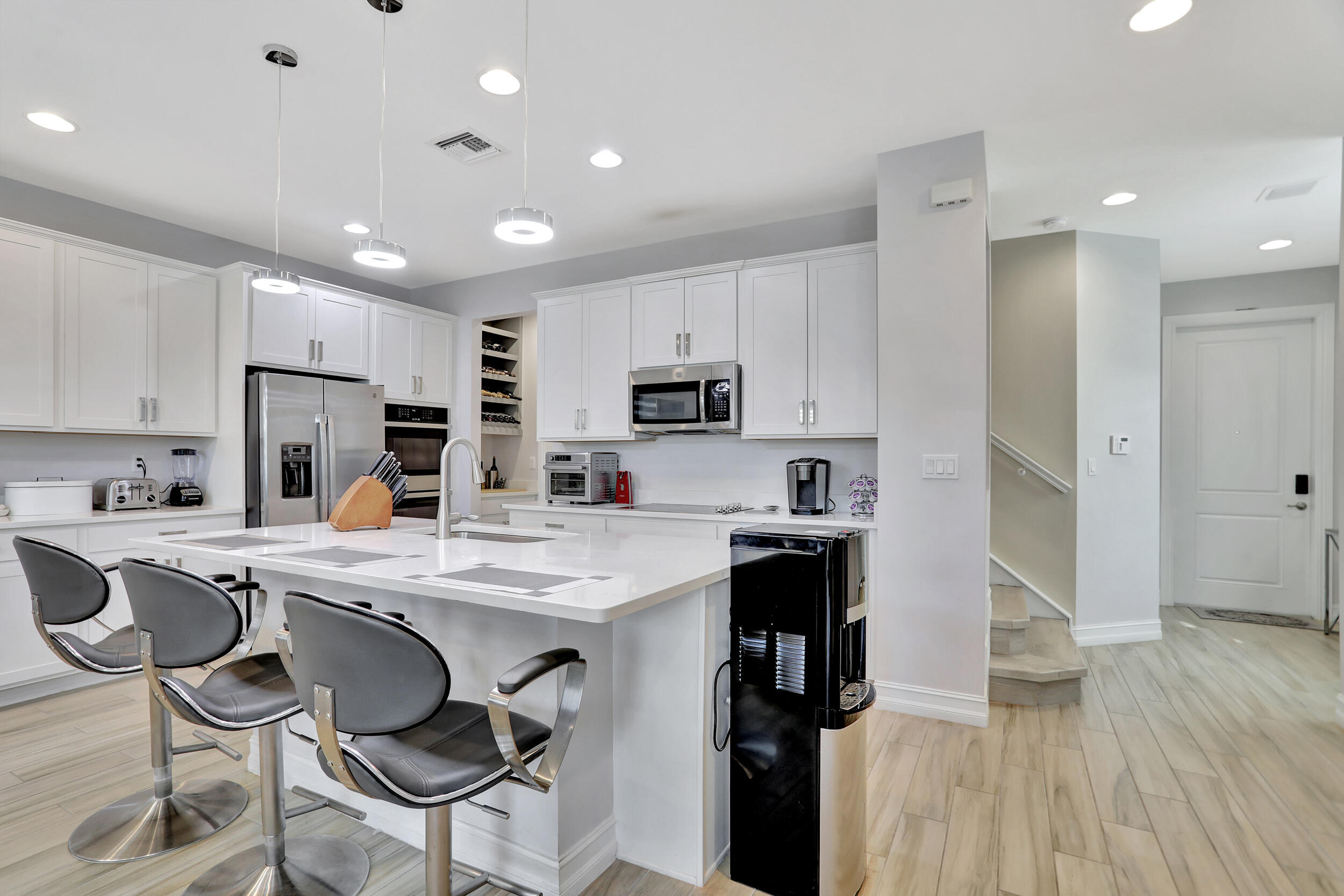 9517 Glider Way Boca Raton, FL 33428 - Photo 12 of 60 a kitchen with a sink a stove a refrigerator and white cabinets with wooden floor