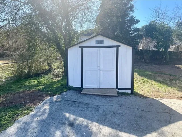 a wooden door in front of a house with large trees