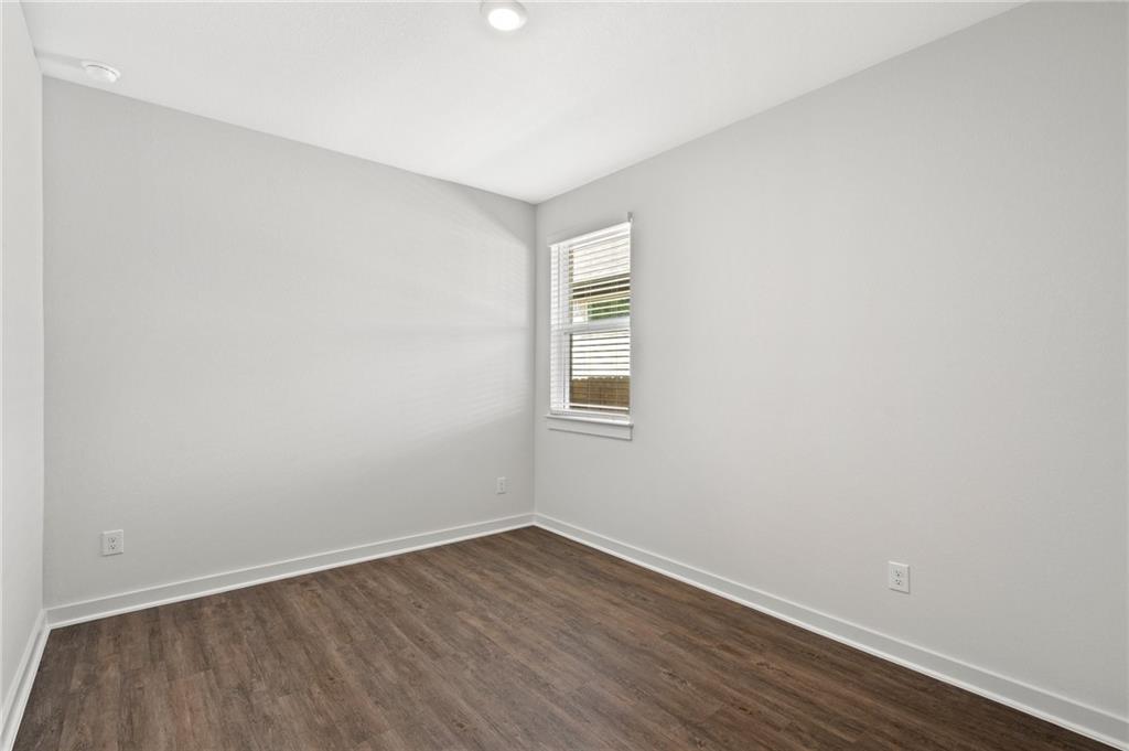 1012 Paddock Lane Georgetown, TX 78626 - Photo 9 of 15 A well-lit bedroom featuring durable plank flooring and a single window for natural illumination.