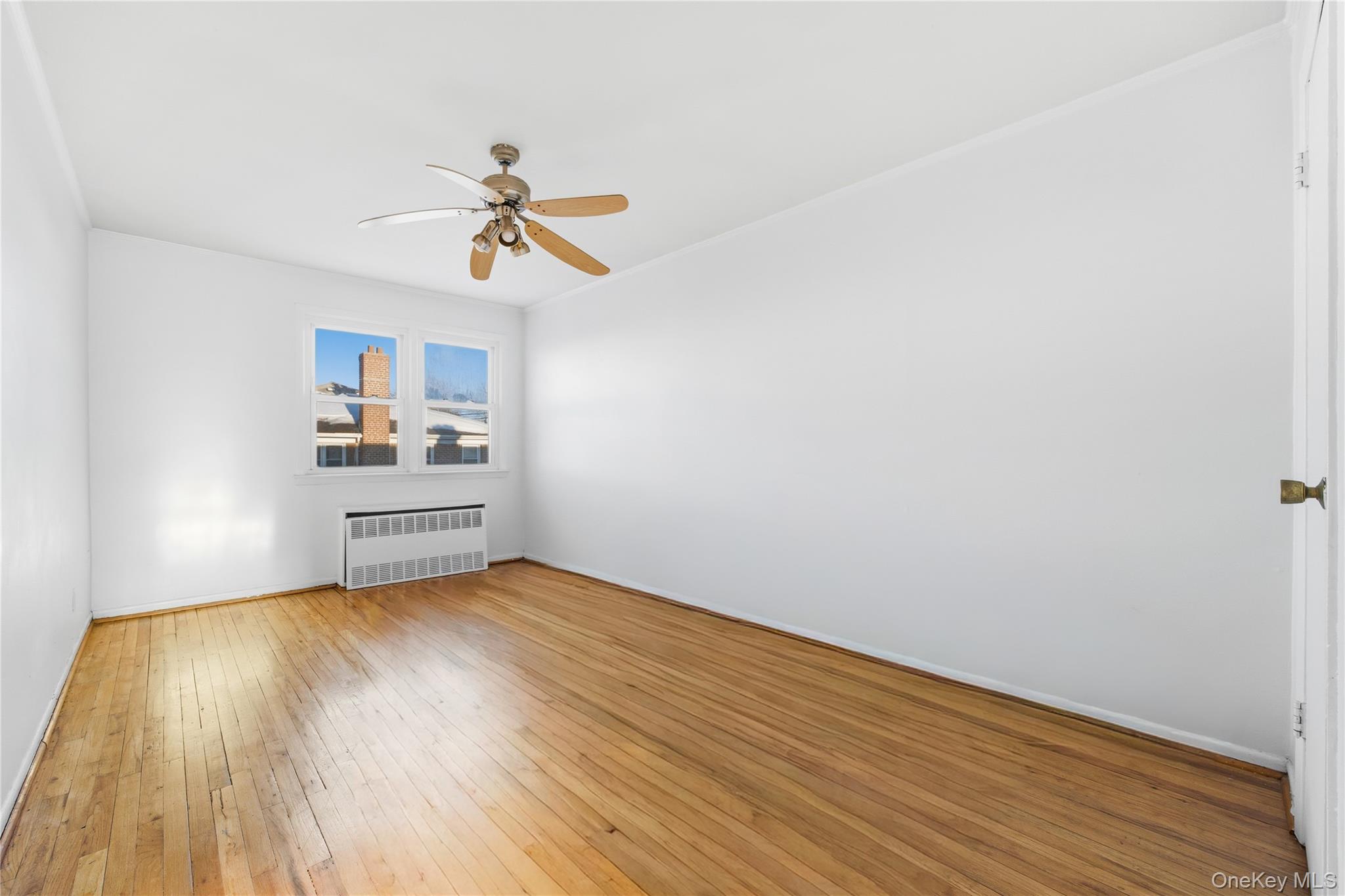 5-37 117th Street Queens, NY 11356 - Photo 11 of 28 a view of a room with wooden floor and a ceiling fan