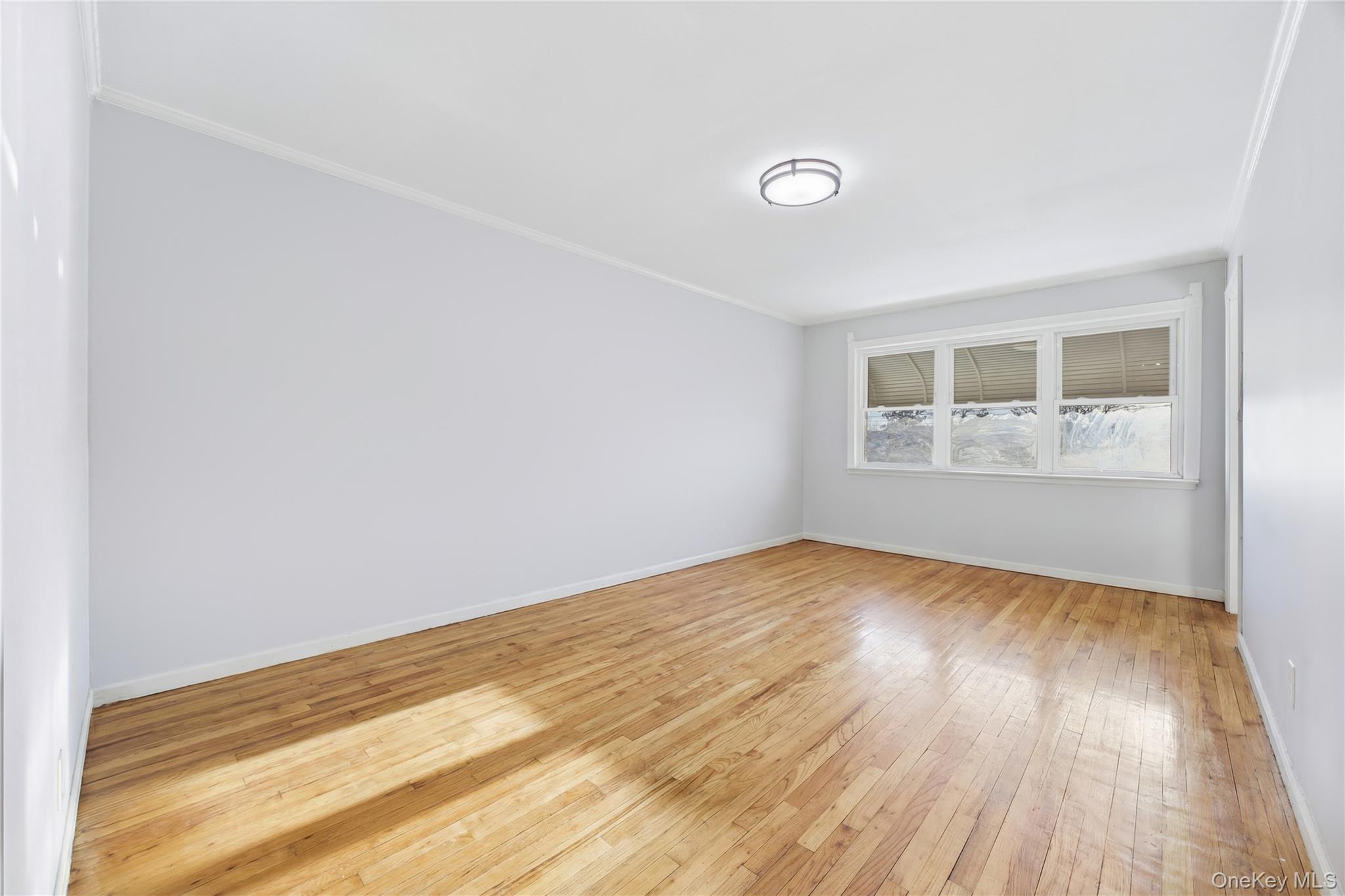 5-37 117th Street Queens, NY 11356 - Photo 6 of 28 a view of empty room with wooden floor and fan