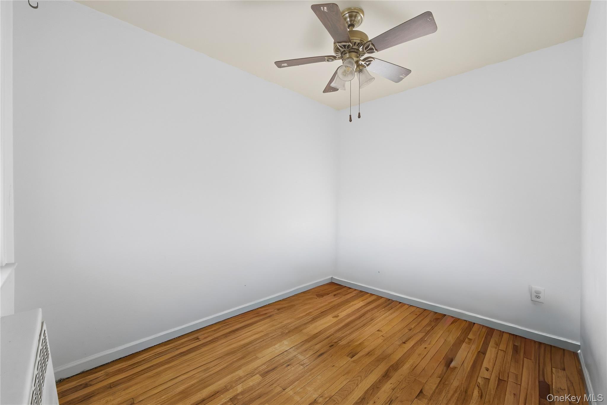 5-37 117th Street Queens, NY 11356 - Photo 8 of 28 a view of a room with wooden floor and a ceiling fan