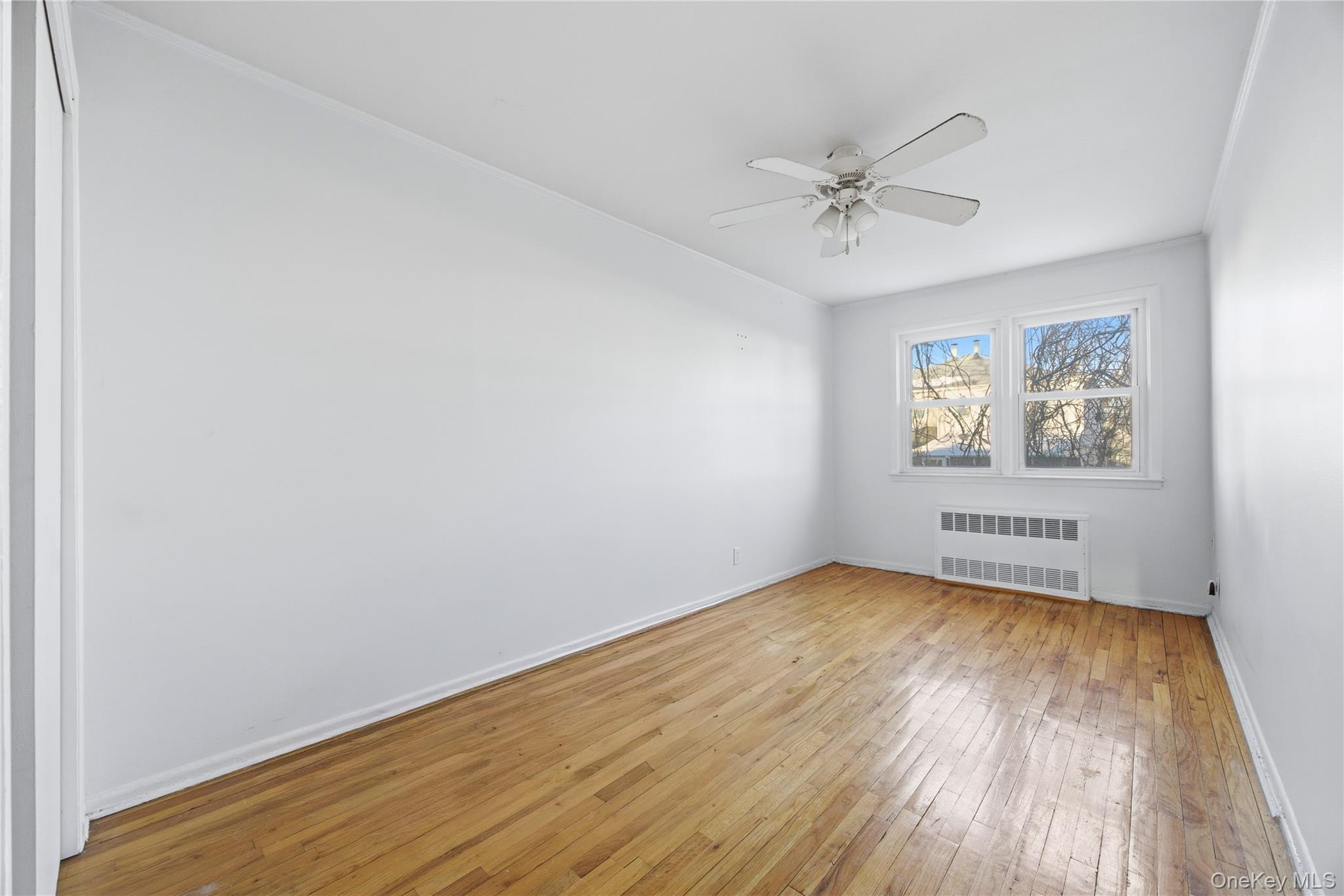 5-37 117th Street Queens, NY 11356 - Photo 9 of 28 an empty room with windows and fan