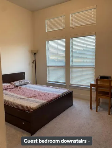 a bedroom with a bed table chair and a window