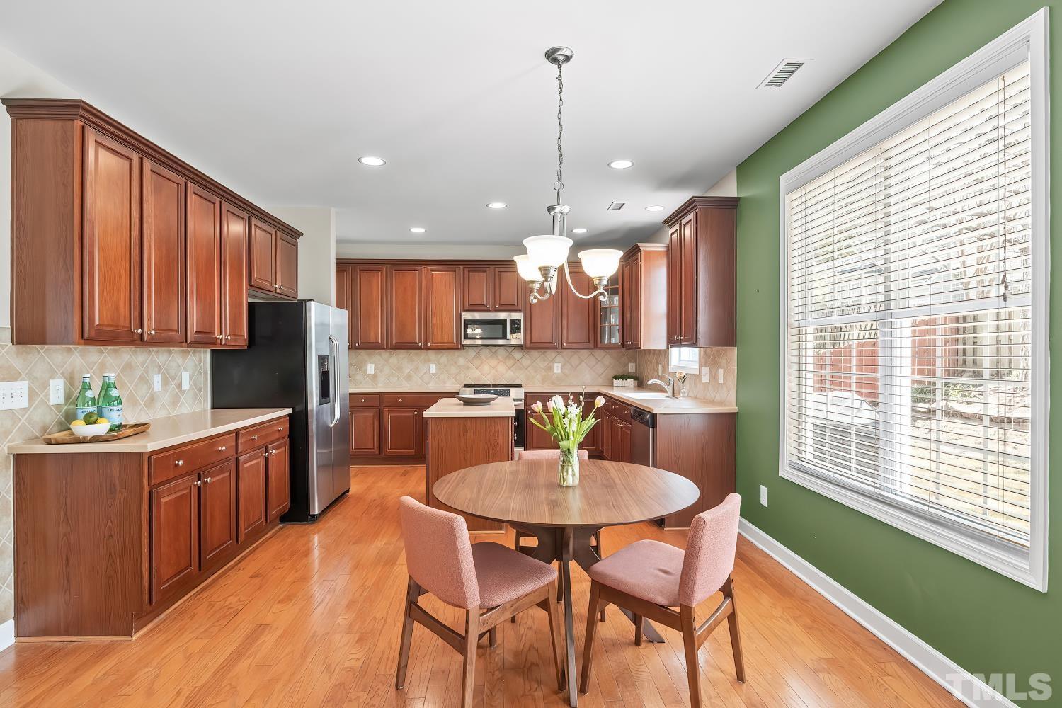 5225 Holly Ridge Farm Road Raleigh, NC 27616 - Photo 15 of 61 a kitchen with stainless steel appliances granite countertop a stove a sink a kitchen island with chairs and wooden cabinets