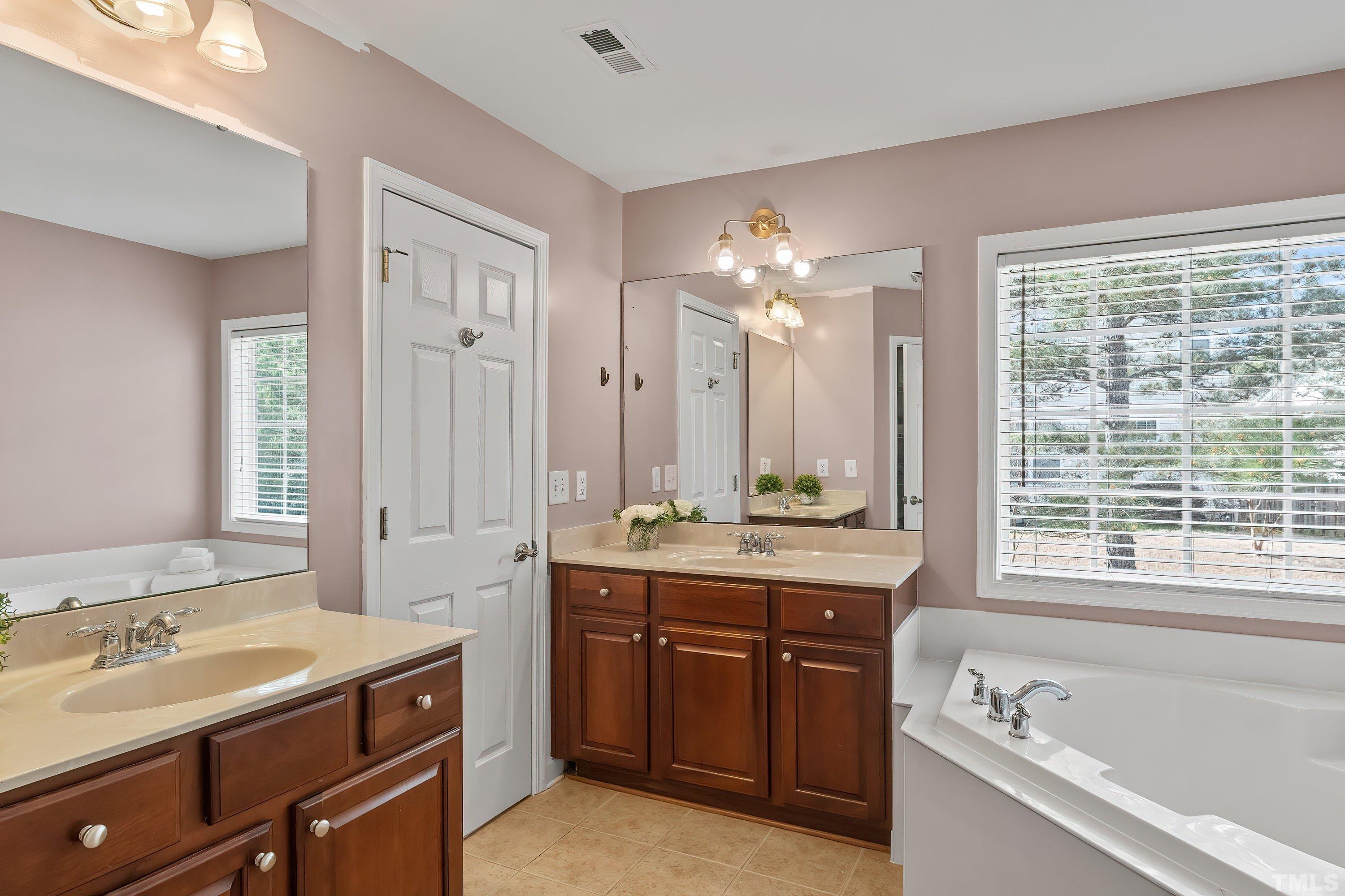 5225 Holly Ridge Farm Road Raleigh, NC 27616 - Photo 32 of 61 a bathroom with a tub sink double vanity granite and a large mirror