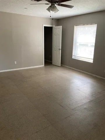 an empty room with a chandelier fan and windows