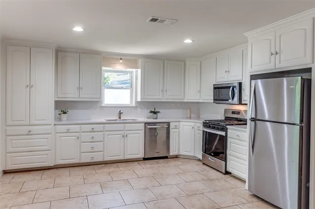 a kitchen with white cabinets stainless steel appliances