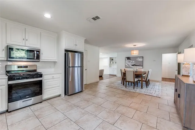 a kitchen with stainless steel appliances granite countertop a stove a refrigerator a microwave a dining table and chairs