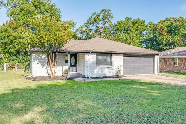 a front view of a house with a garden and trees