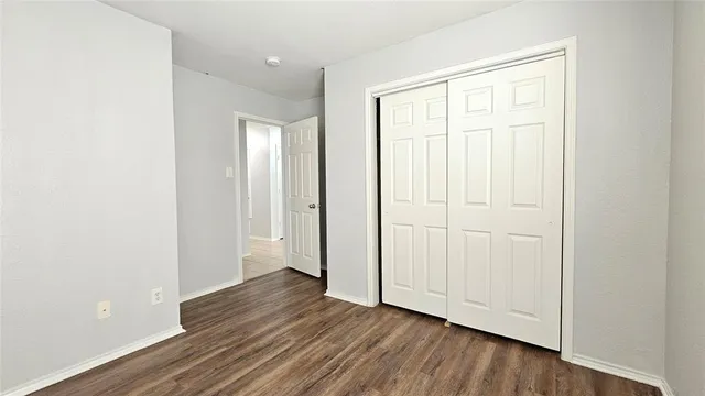 an empty room with wooden floor and closet area