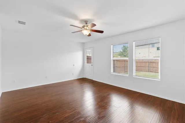a view of an empty room with a window and wooden floor