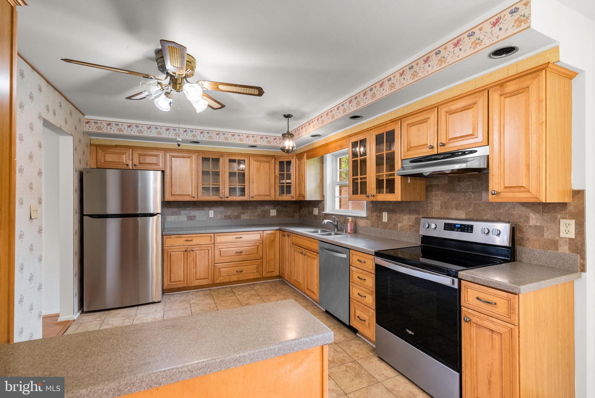 18724 Bloomfield Road Olney, MD 20832 - Photo 6 of 32 a kitchen with stainless steel appliances granite countertop a refrigerator a sink dishwasher a stove and white cabinets with wooden floor