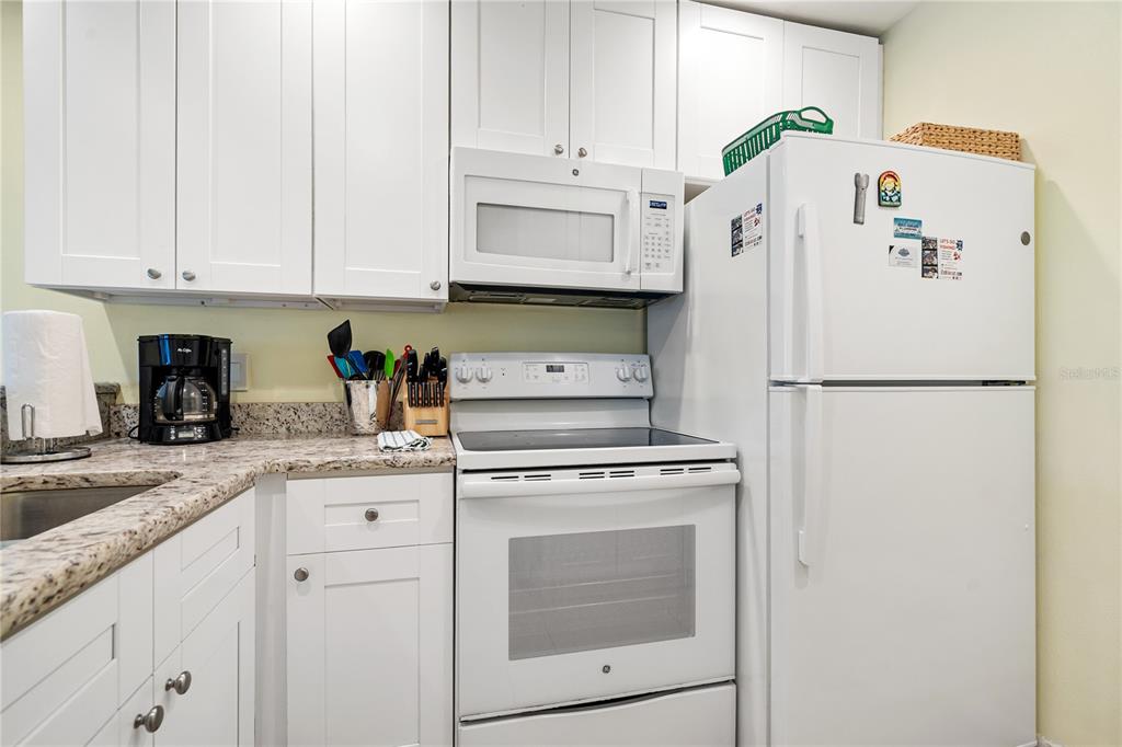 230 Medallion Boulevard, Unit E Madeira Beach, FL 33708 - Photo 11 of 35 a kitchen with granite countertop white cabinets and refrigerator