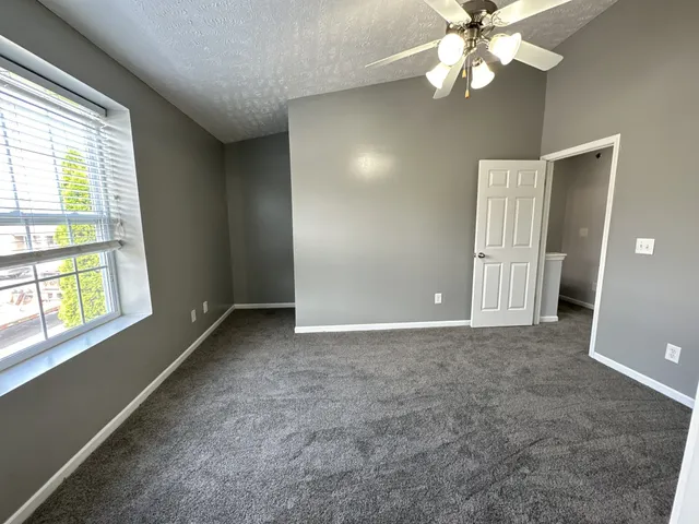 an empty room with windows and fan