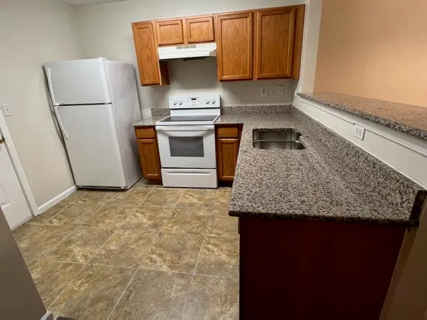 a kitchen with granite countertop a refrigerator a stove and a sink