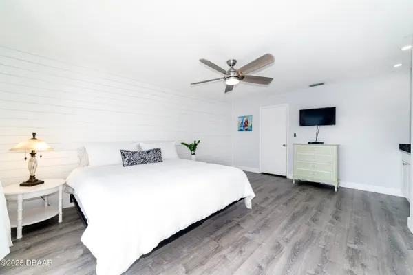 a spacious bedroom with a bed and a tv on the dresser