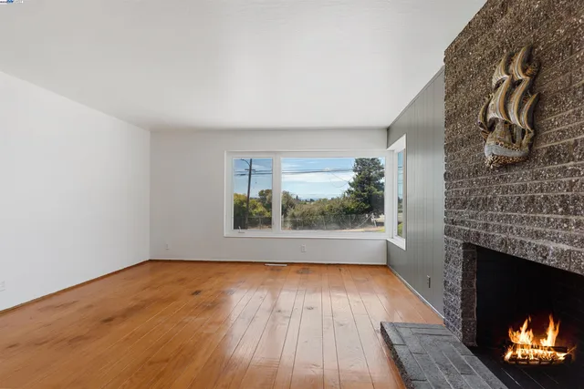 a view of empty room with wooden floor and fireplace