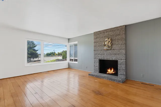 a view of an empty room with wooden floor and a fireplace