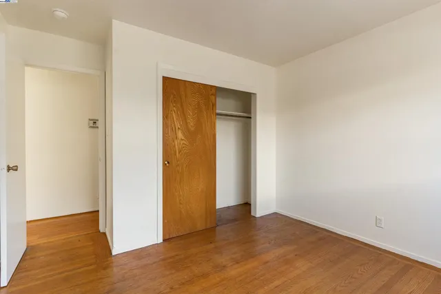 a view of an empty room with wooden floor and closet