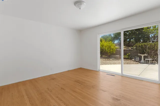 a view of an empty room with wooden floor and a floor to ceiling window