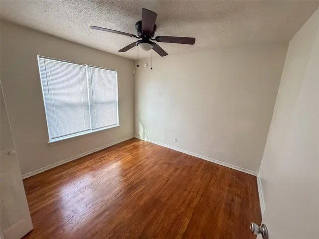 an empty room with wooden floor fan and windows