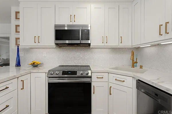 a kitchen with white cabinets and black appliances