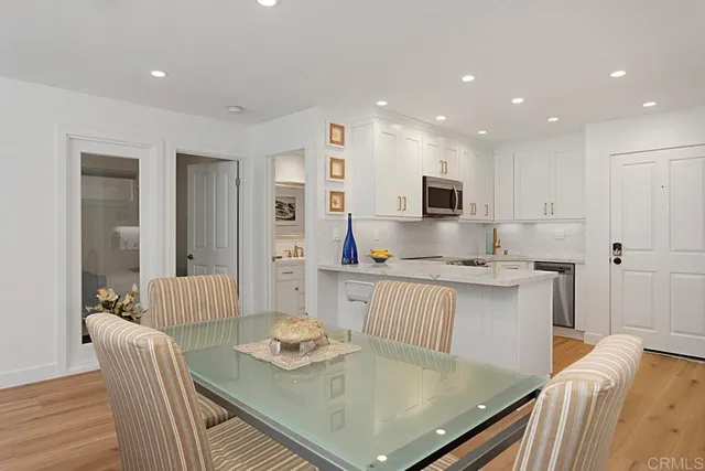 a kitchen with stainless steel appliances granite countertop a stove a table and chairs with wooden floor