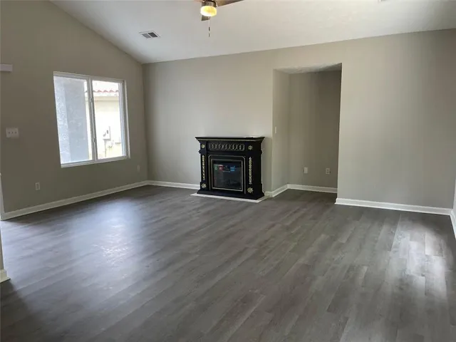 an empty room with wooden floor fireplace and windows