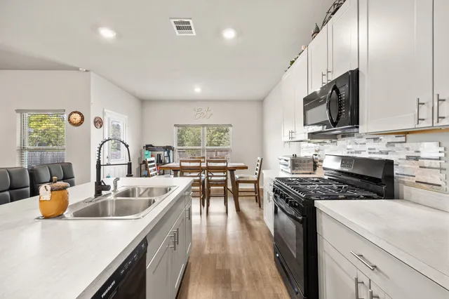 a kitchen with stainless steel appliances granite countertop a sink stove and cabinets