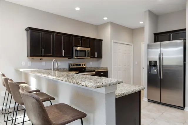 a kitchen with granite countertop a refrigerator stove microwave and sink