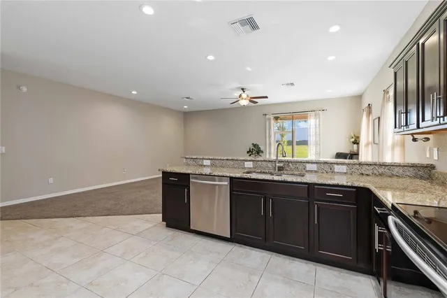 a large kitchen with granite countertop a sink and dishwasher a stove top oven with wooden floor