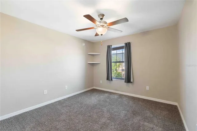 an empty room with a window and a ceiling fan