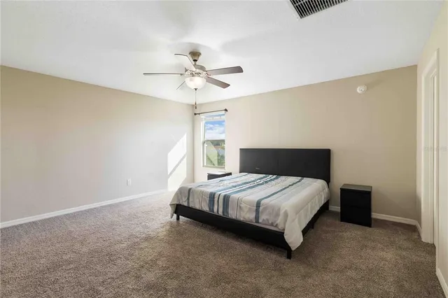 a bedroom with a bed lamp and a ceiling fan