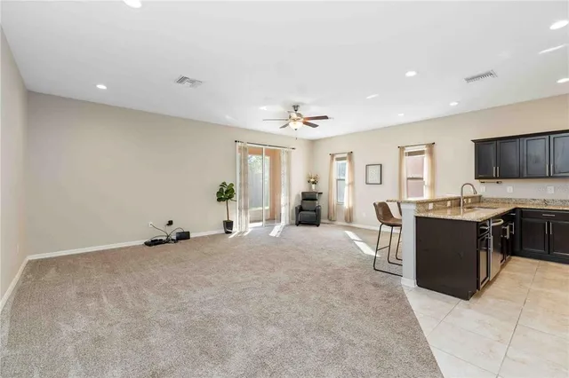 a large white kitchen with stainless steel appliances granite countertop a large counter top a stove and a refrigerator with wooden floor