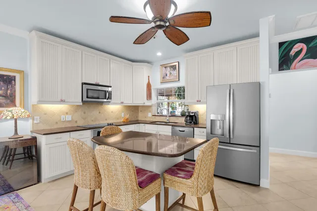 a kitchen with stainless steel appliances granite countertop a stove a refrigerator a sink a dining table and chairs