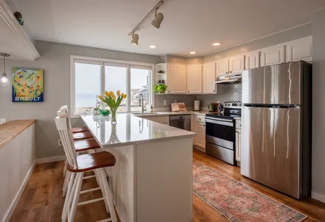 a kitchen with stainless steel appliances granite countertop a refrigerator a stove a sink a dining table and chairs with wooden floor