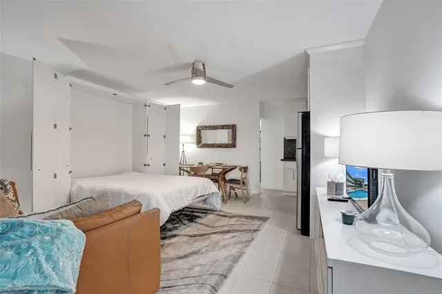 a spacious bedroom with a bed a lamp and a flat screen tv