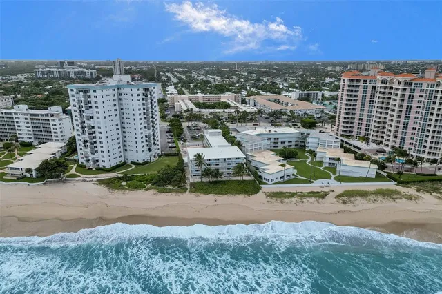 an aerial view of residential houses with outdoor space and ocean view