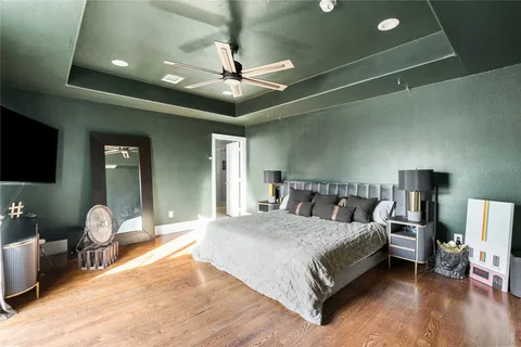 a spacious bedroom with a bed and a flat tv screen on dresser