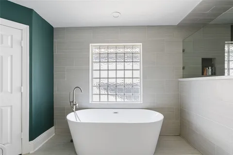 a white bath tub sitting in a bathroom next to a window
