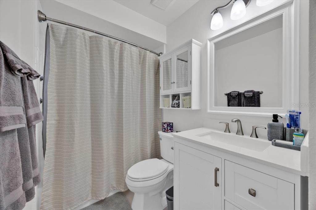 5734 Delano Lane Orlando, FL 32821 - Photo 17 of 28 a bathroom with a sink a toilet a mirror and shower curtain