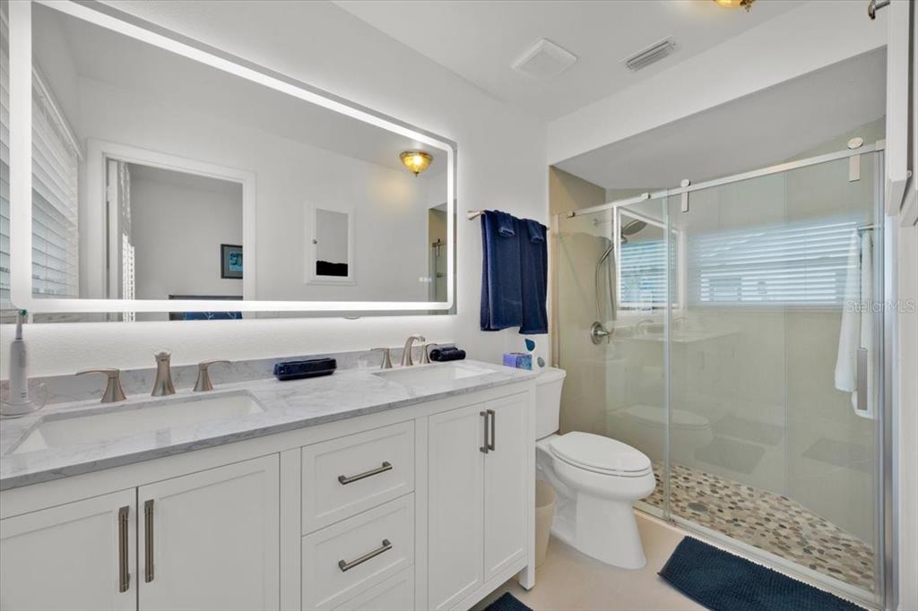 5734 Delano Lane Orlando, FL 32821 - Photo 20 of 28 a bathroom with a double vanity sink toilet mirror and shower