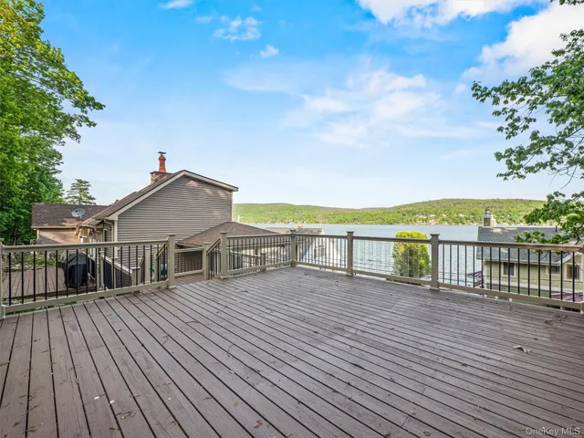 a view of a house with wooden deck and a large trees